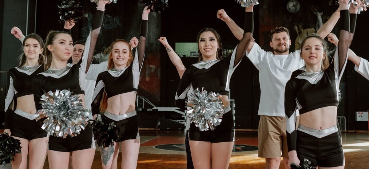 Energetic cheerleading team performing indoors with pompoms and uniforms.