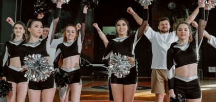 Energetic cheerleading team performing indoors with pompoms and uniforms.