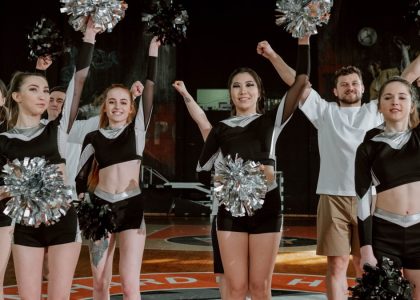 Energetic cheerleading team performing indoors with pompoms and uniforms.