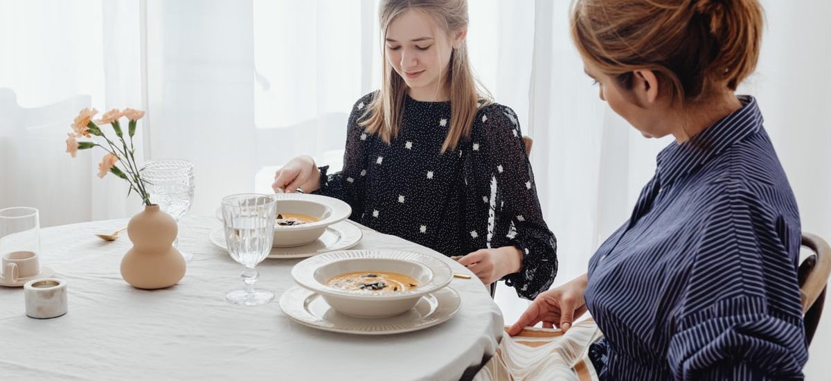 A serene scene of a mother and daughter dining together in a bright, cozy setting.