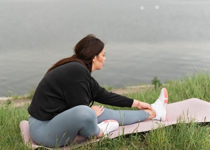 A woman stretches on a yoga mat by a serene lake, embodying relaxation and wellness in nature.